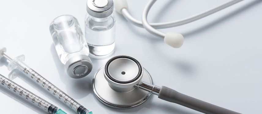 various medical supplies on table including needles, vials and stethoscope